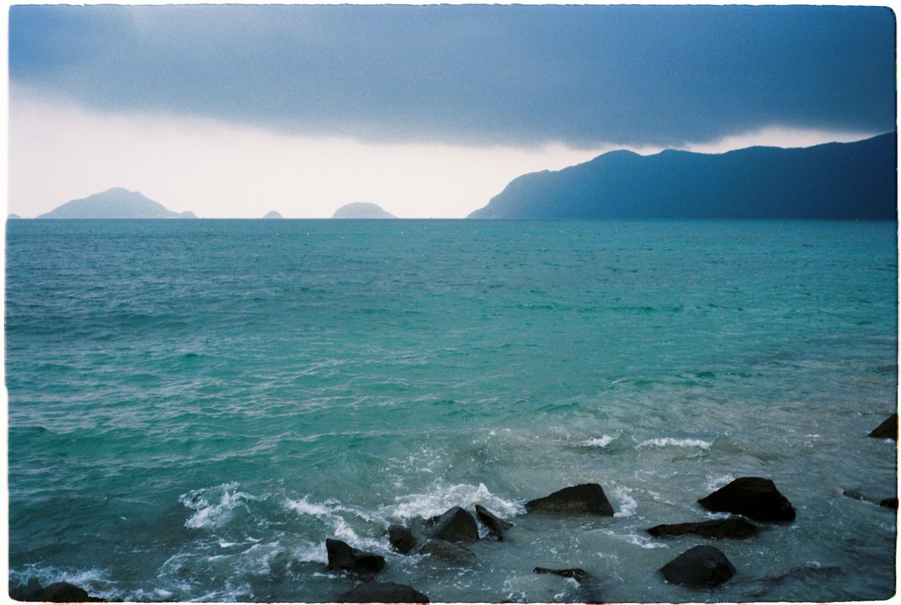 Con Dao — Dramatic seascape with rocky shore and distant islands in Vietnam.