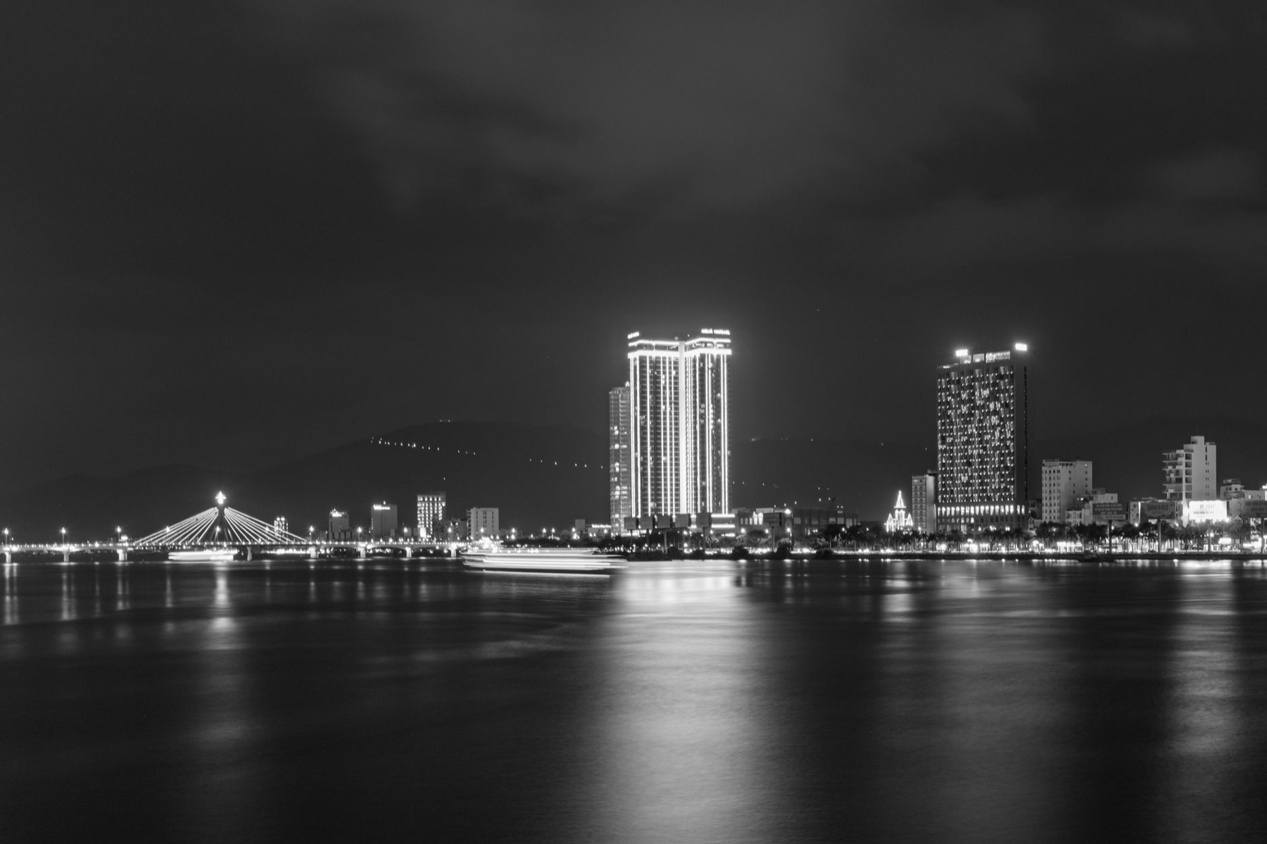 Da Nang — Stunning nighttime cityscape with illuminated bridge and skyscrapers reflecting