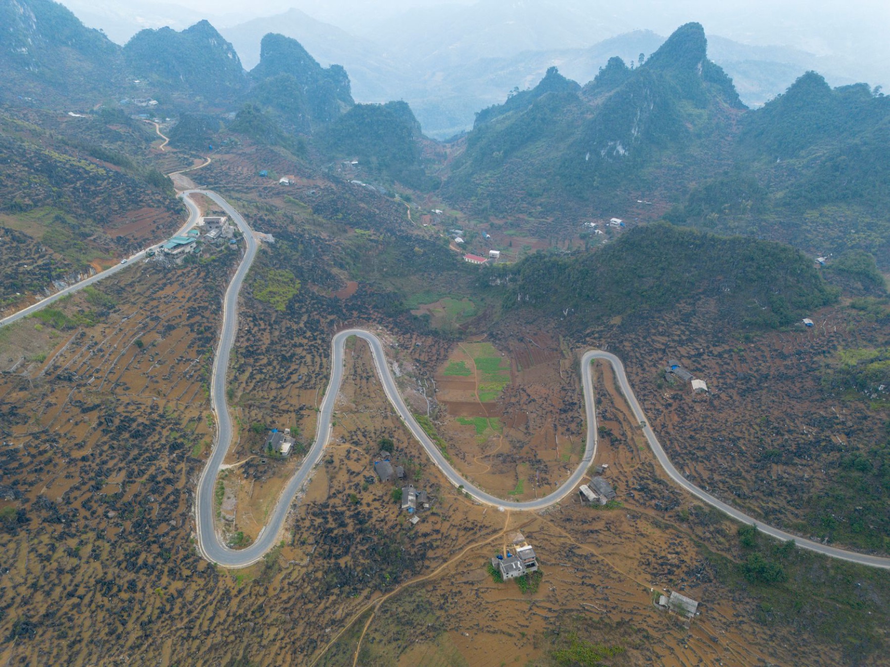 Ha Giang — Aerial view of a winding mountain road in Ha Giang, Vietnam, showcasing stunning