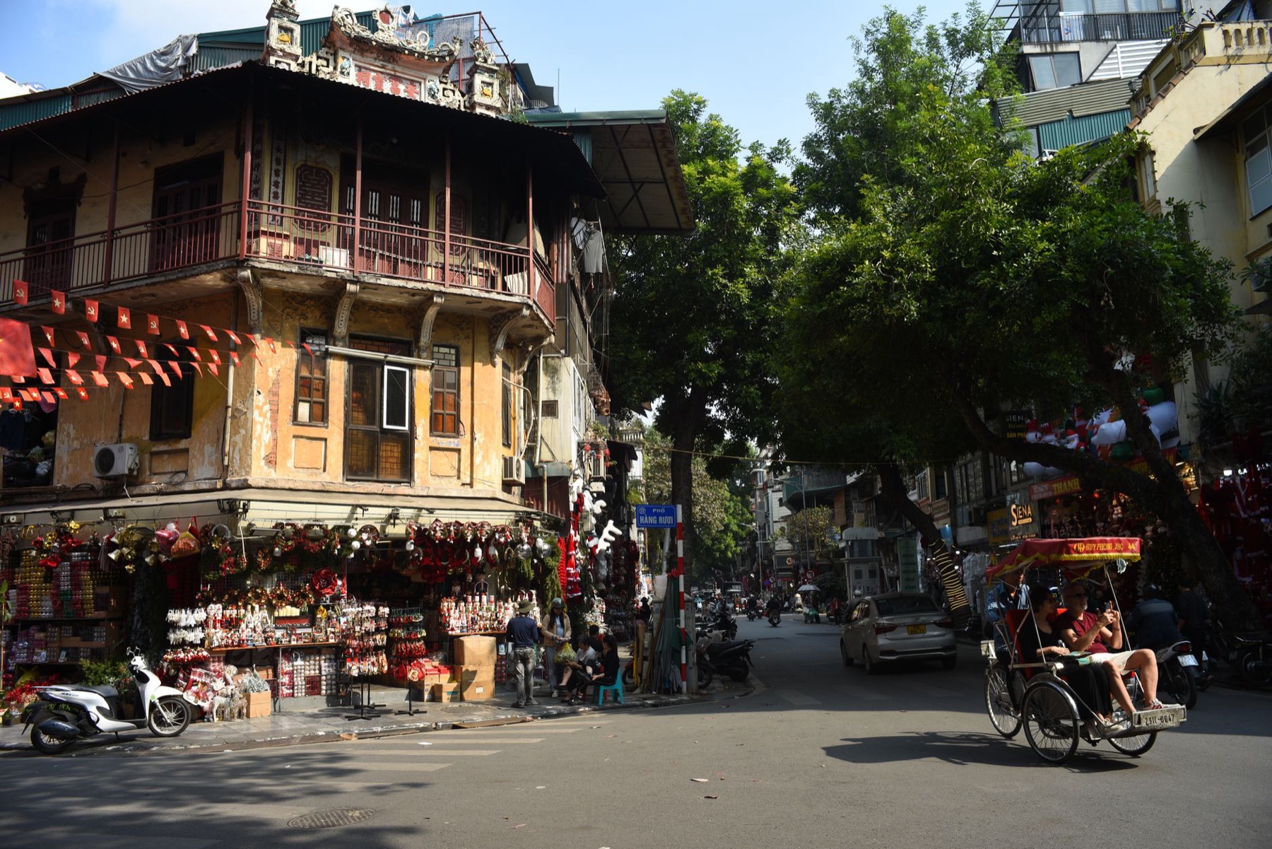 Hanoi — Lively street corner in Hanoi featuring traditional architecture and a passing r