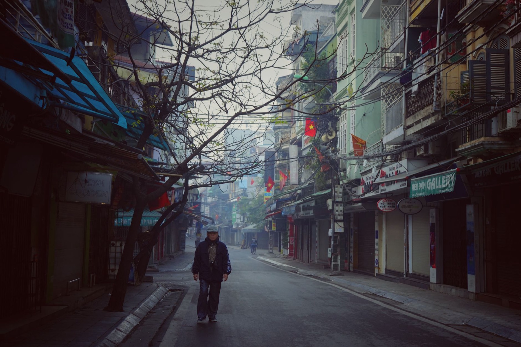 Hanoi — Moody street view of a Vietnamese town with a lone pedestrian on a quiet street.