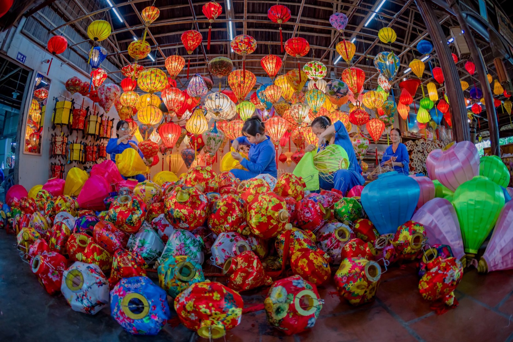 Hoi An — Vibrant display of traditional lanterns with artisans working indoors in a livel