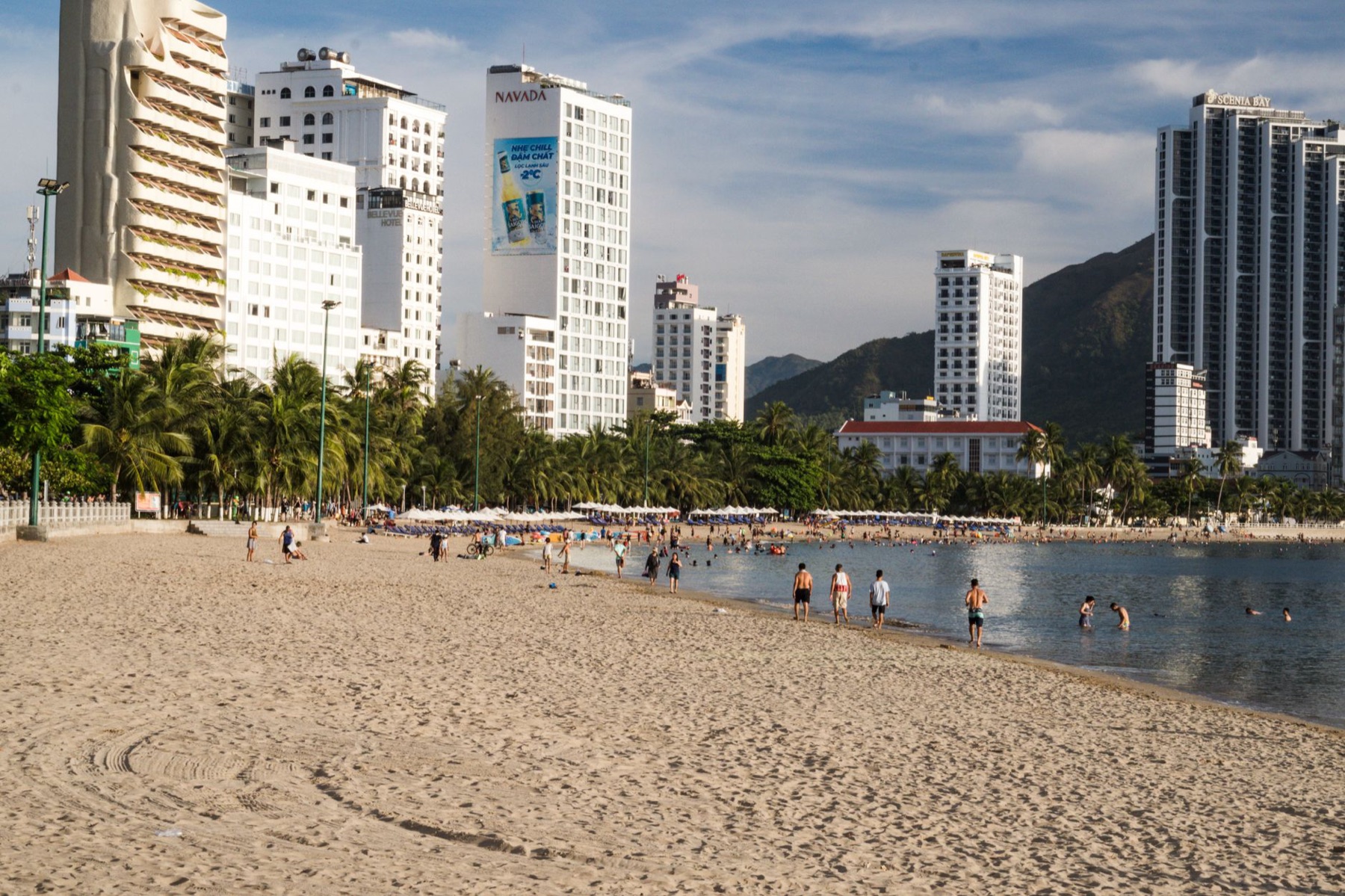 Nha Trang — Urban beachfront scene with tall hotels, palm trees, and people enjoying a sunny