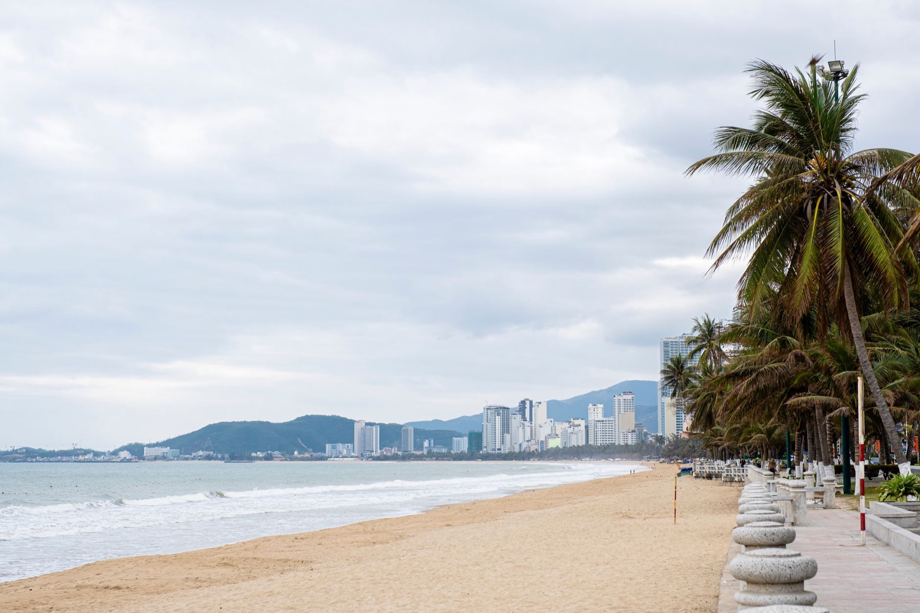 Nha Trang — Scenery of ocean shore with sandy beach and green palms near embankment in cloud