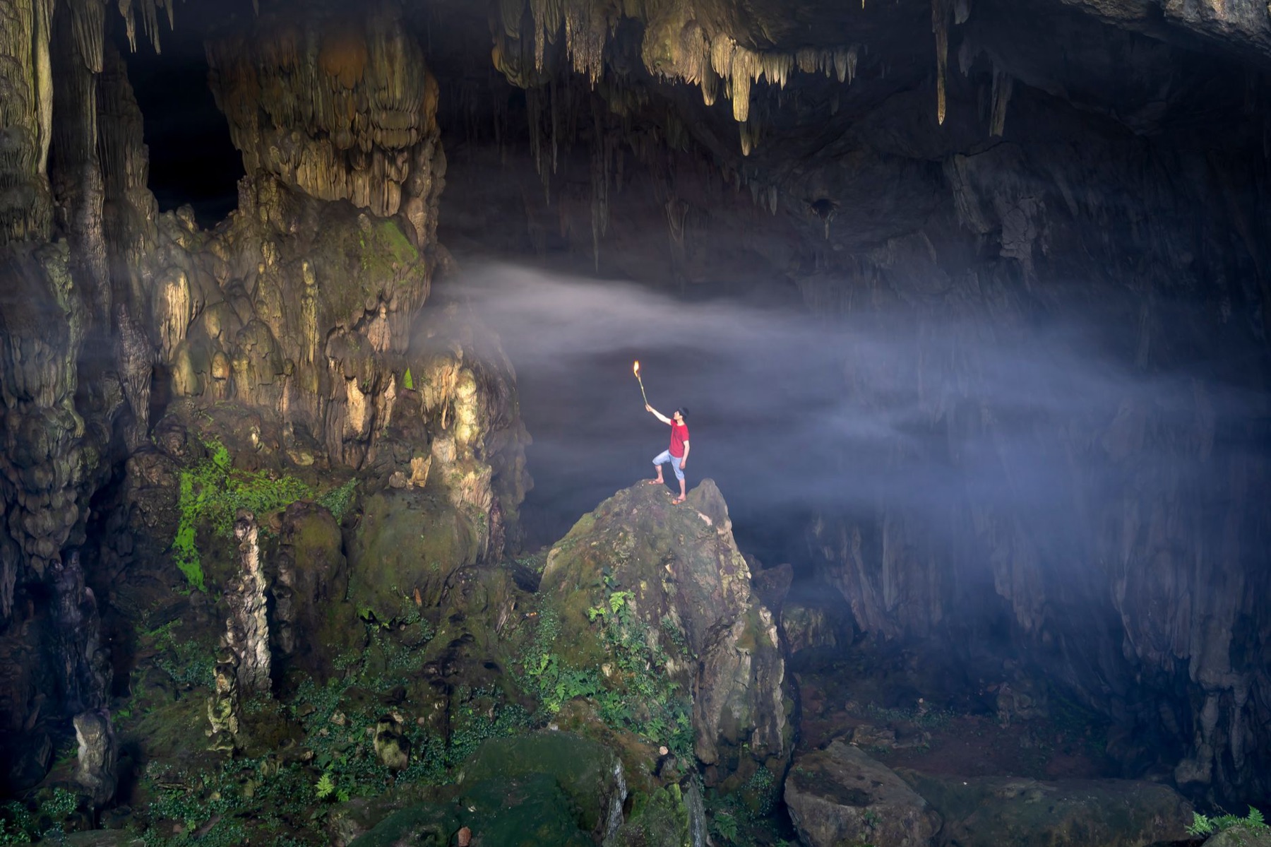 Phong Nha — A lone explorer with a torch stands inside a magnificent cave in Son La, Vietnam