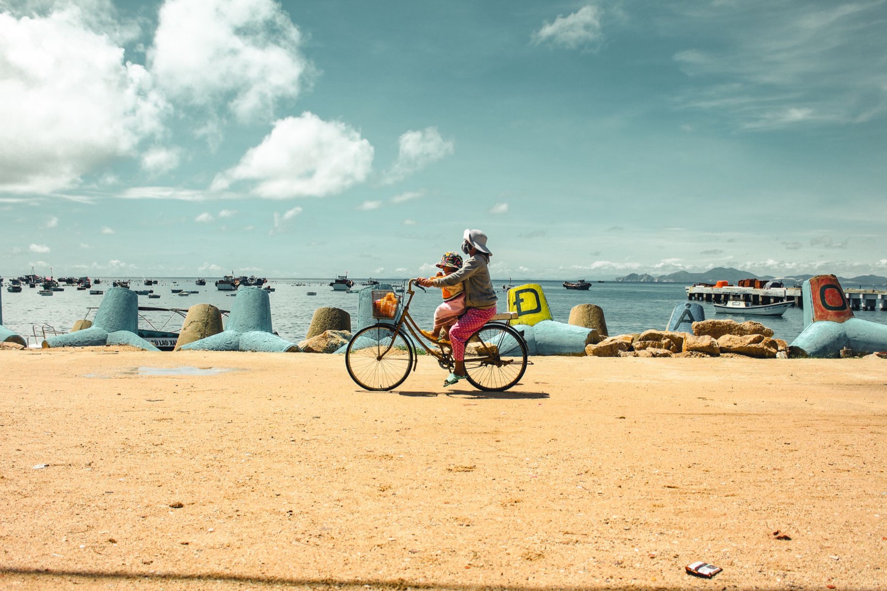 Quy Nhon — Enjoy a sunny day as a woman cycles along the picturesque Qui Nhơn beach, Vietna